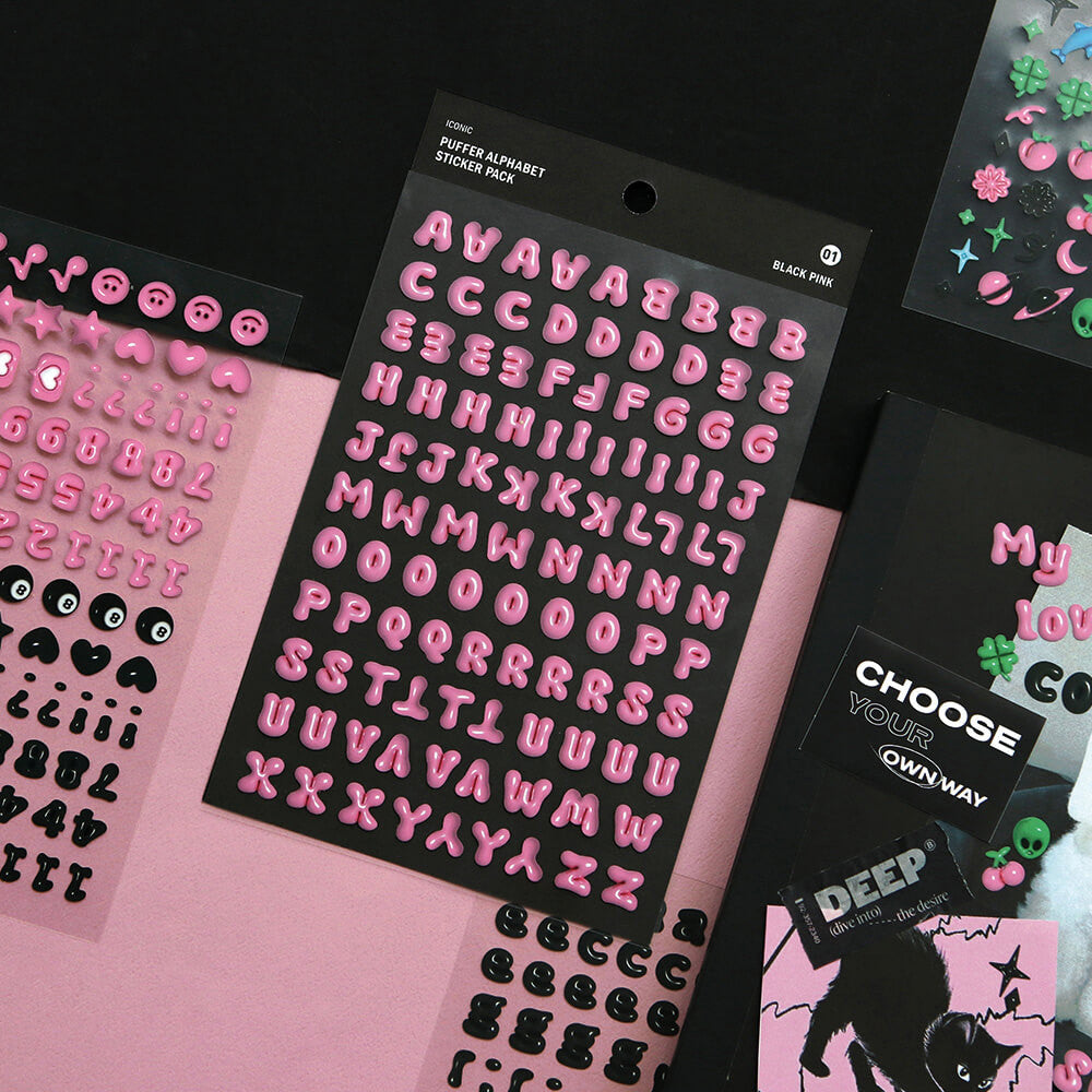 The Journal Shop - Iconic Puffer Alphabet Sticker sheets in black and pink displayed on a dark black desk.
