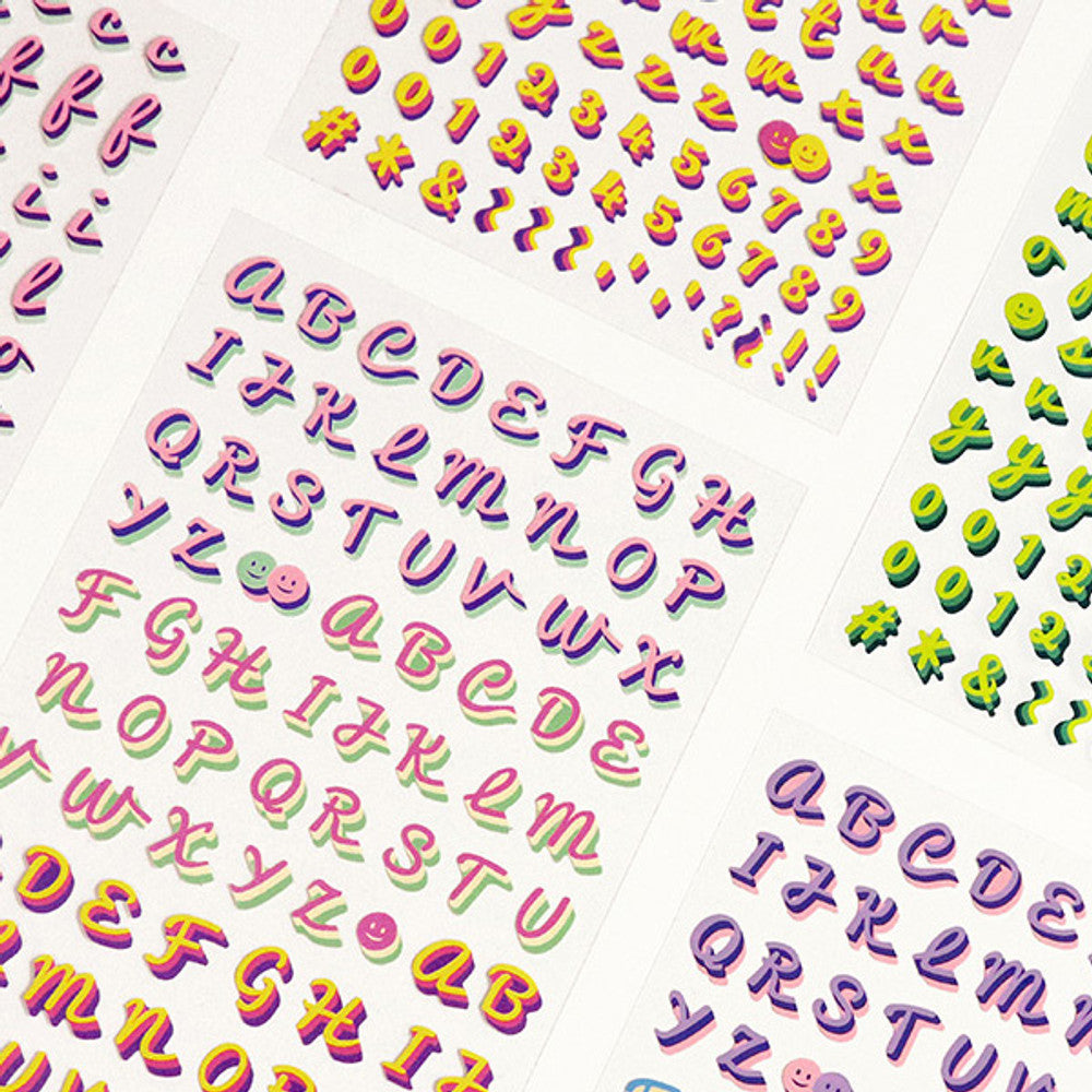 The Journal Shop - Alphabet stickers in purple, orange, and green hues arranged neatly on a desk surface.
