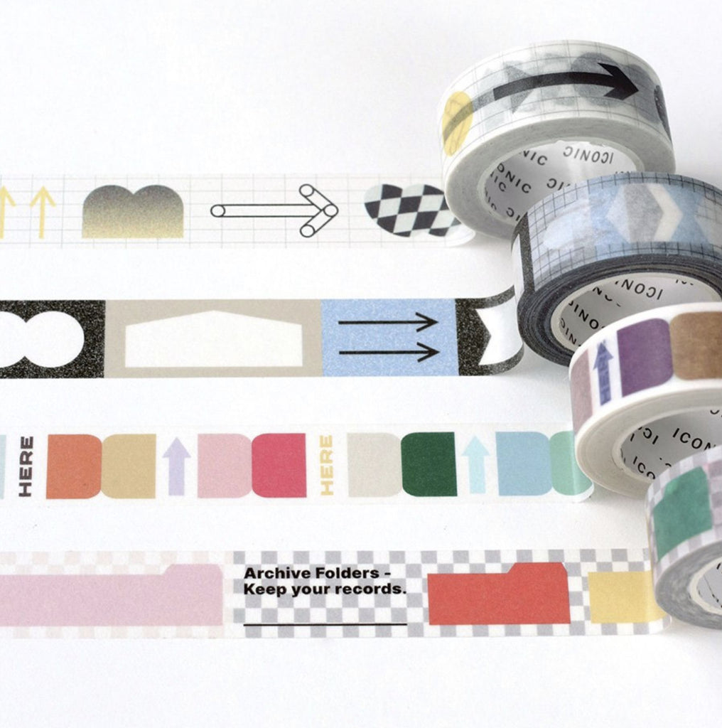 The Journal Shop - A collection of Iconic Shape Masking Tapes unrolled on a white surface, showing colourful geometric and patterned designs including arrows, tags, and checkered shapes.