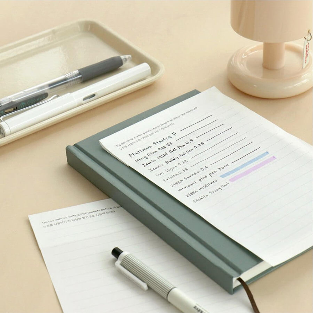The Journal Shop - Iconic Solitude Tomoe River Line Notebook open beside pens and accessories on desk.