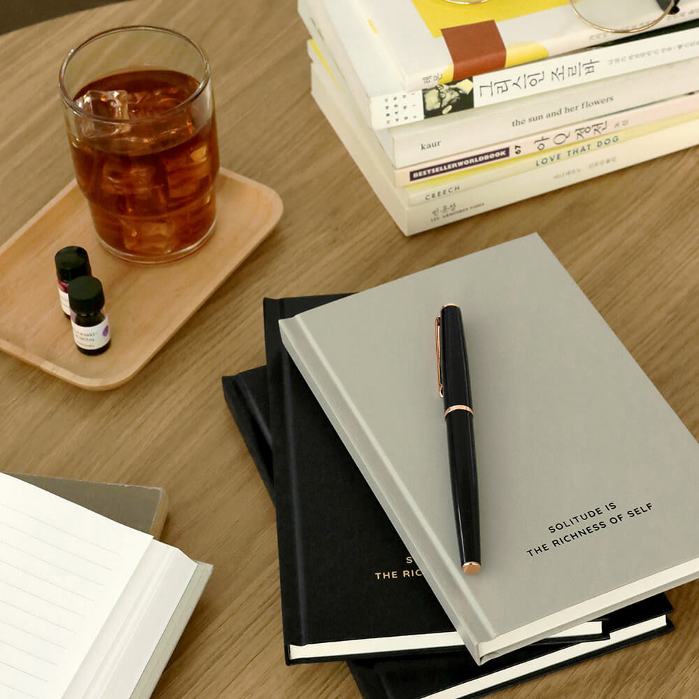 The Journal Shop - Iconic Solitude Tomoe River Line Notebooks in assorted colours placed neatly on a desk with pen and drink.