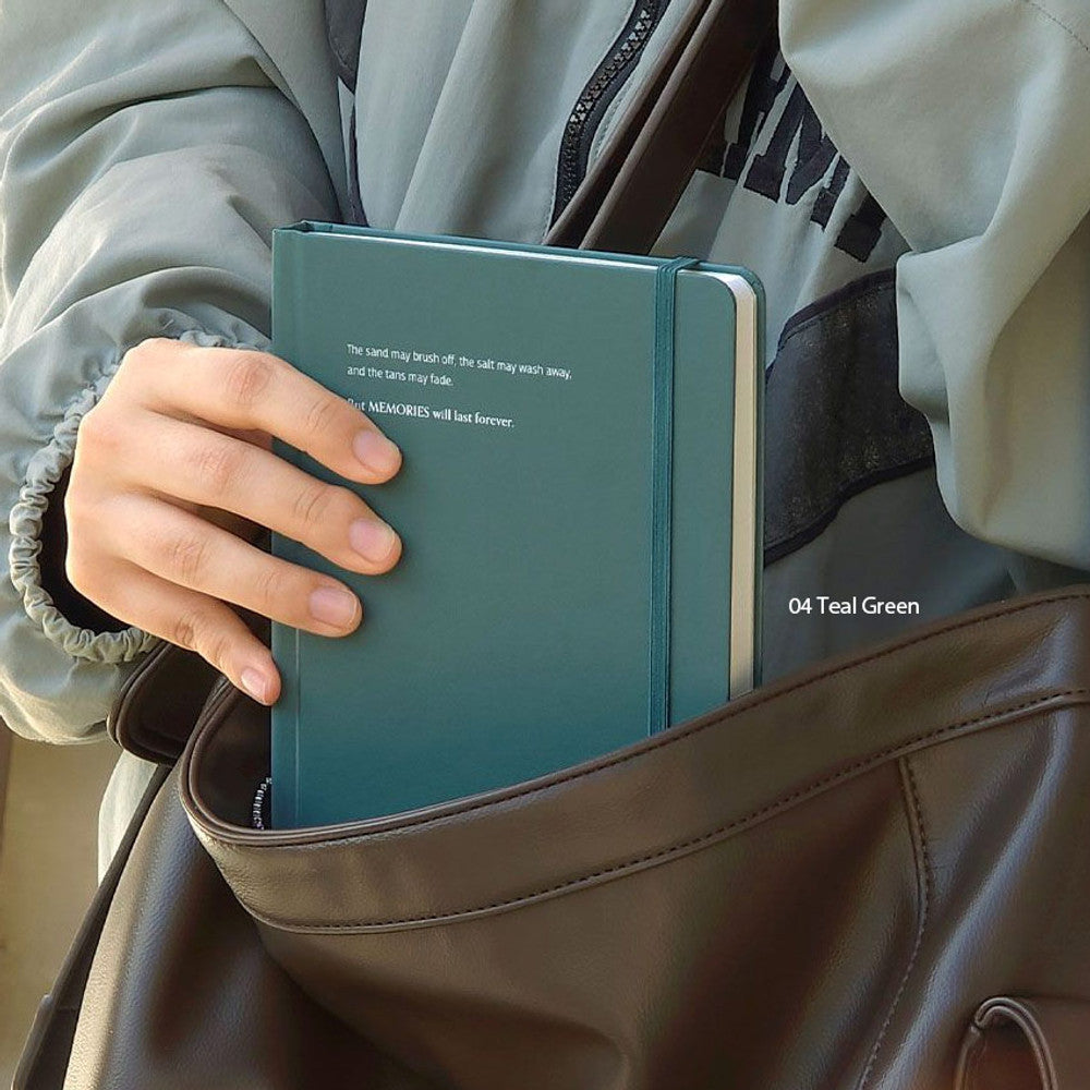 The Journal Shop - Iconic Souvenir B6 Band Notebook dark green hardcover journal being placed into a bag.