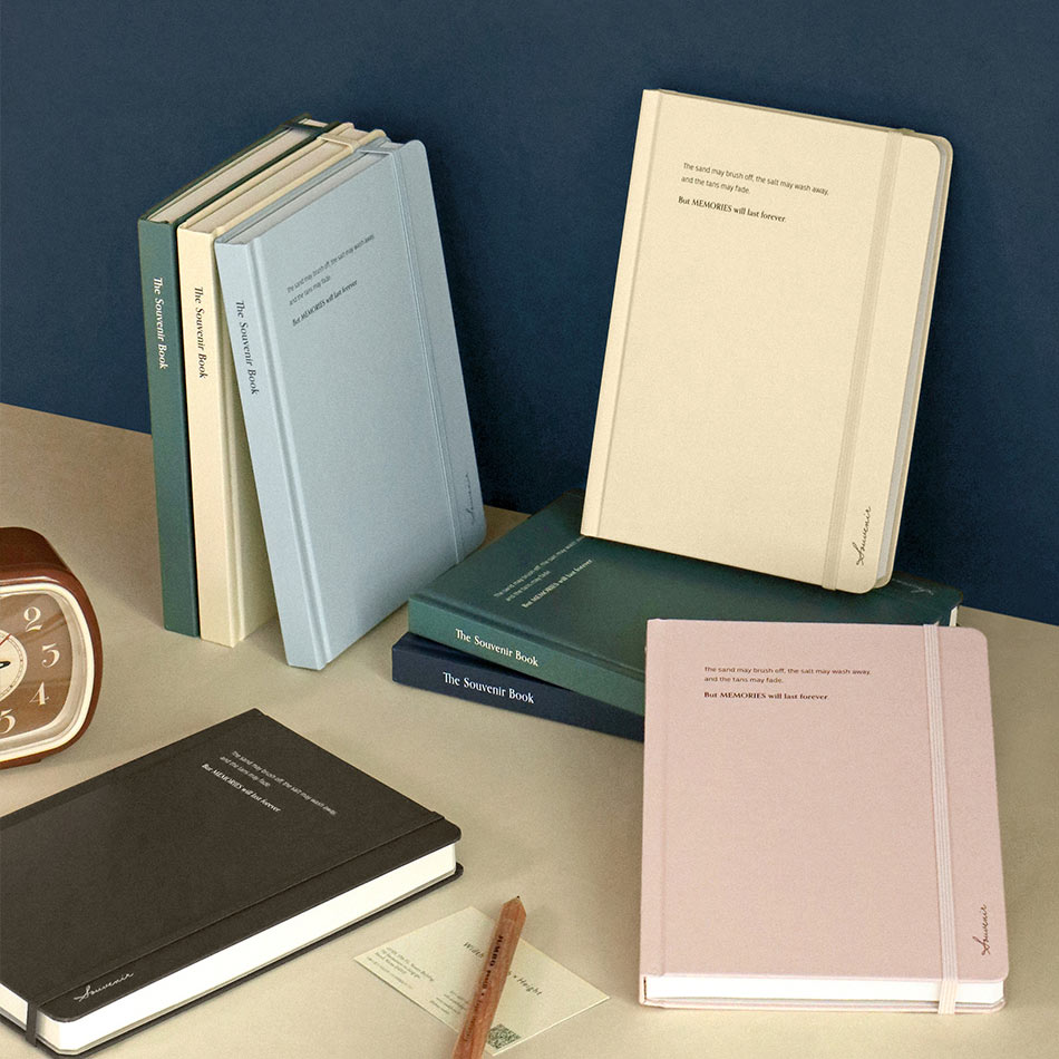 The Journal Shop - Iconic Souvenir B6 Band Notebook lined hardcover journals displayed in assorted colours including pink, beige, blue, and dark green.