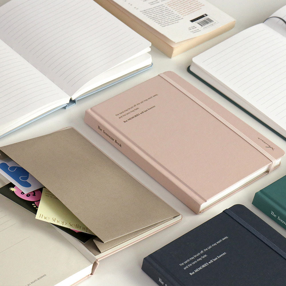 The Journal Shop - Iconic Souvenir B6 Band Notebook lined hardcover journals in assorted colours including pink, beige, green, and navy, shown with open pages and storage pocket.