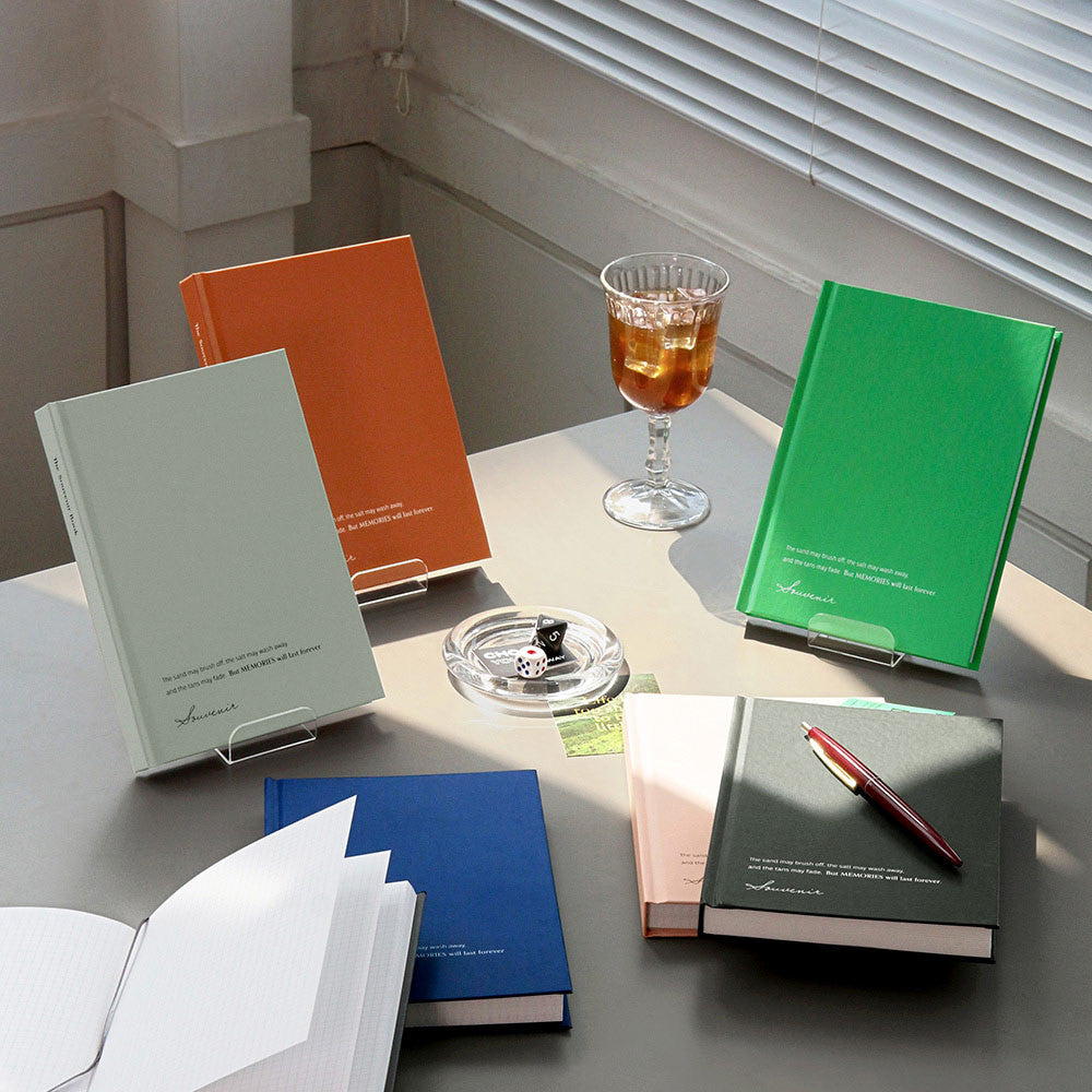The Journal Shop - A collection of Iconic Souvenir B6 Grid Notebooks in orange, green, blue, and black displayed on a bright desk.