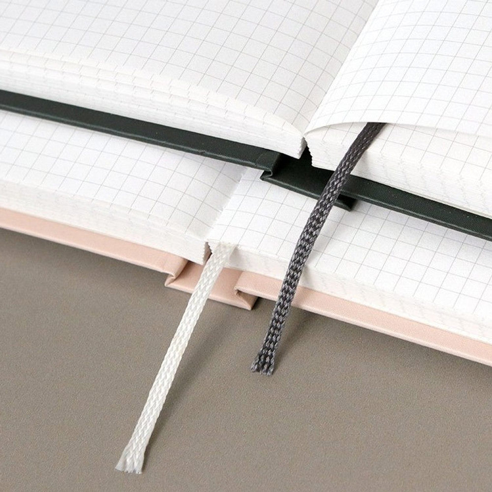 The Journal Shop - Two open Iconic Souvenir B6 Grid Notebooks arranged on a desk, showcasing the light grid paper and smooth binding.