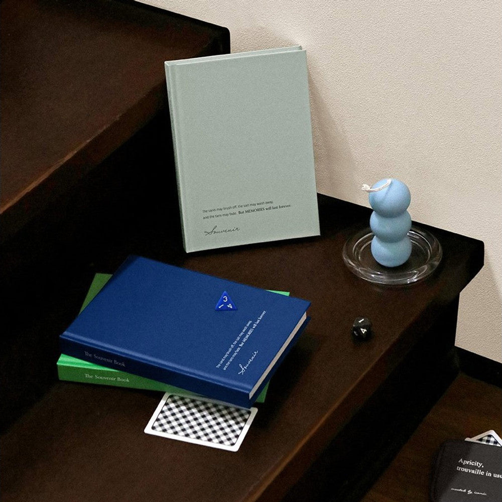 The Journal Shop - A blue and grey Iconic Souvenir B6 Grid Notebook displayed together on a dark desk.