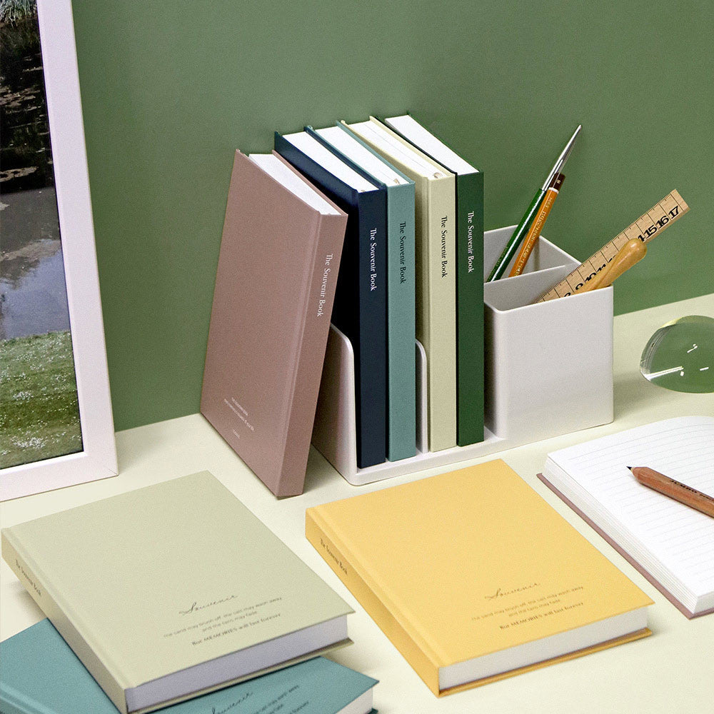 The Journal Shop - Collection of Iconic Souvenir B6 Hardcover Line Notebooks in assorted pastel and deep tones on a desk beside stationery.