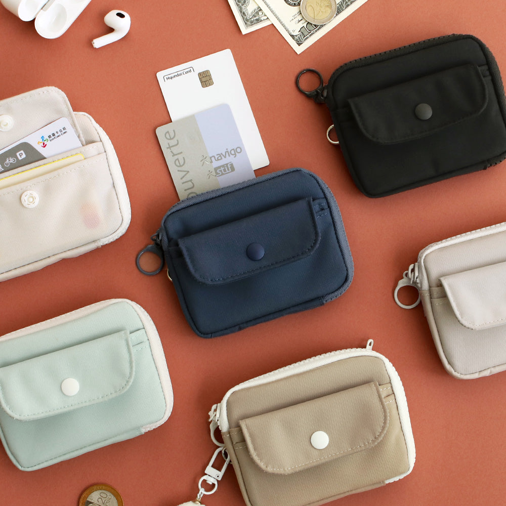 The Journal Shop - Collection of Iconic Voyager Card Wallets in various colours including beige, navy, cream, and black, arranged with travel accessories.