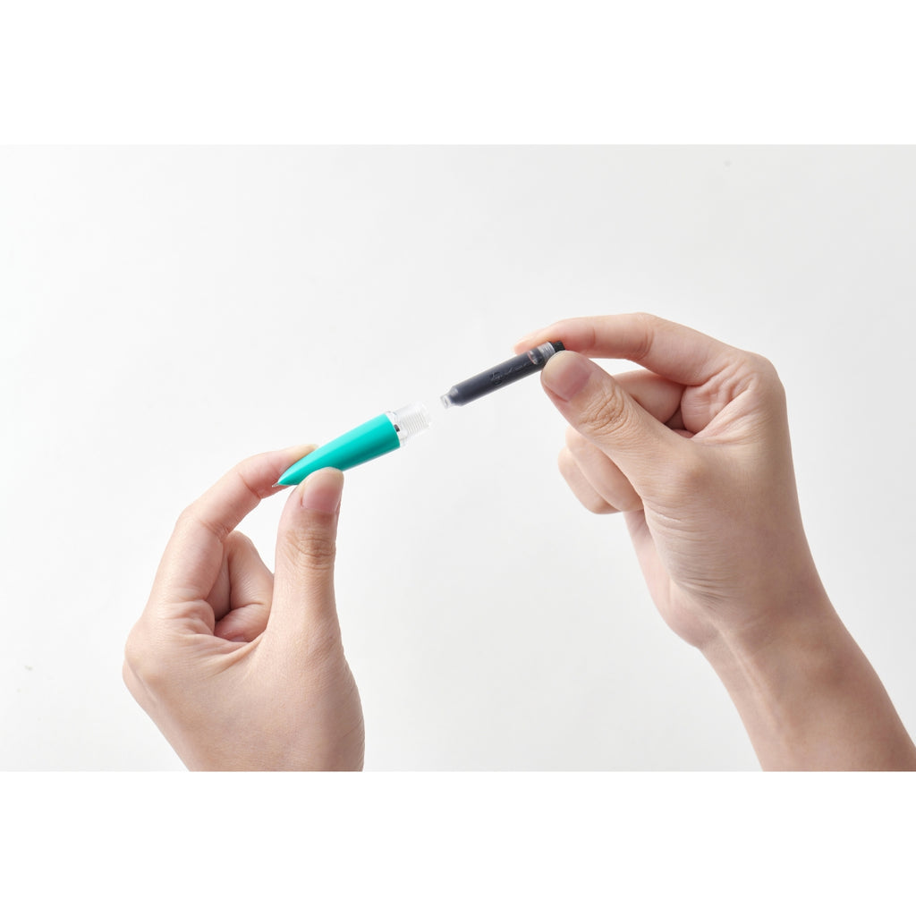 Close-up of hands inserting an ink cartridge into the grip section of a Kaco Retro fountain pen.