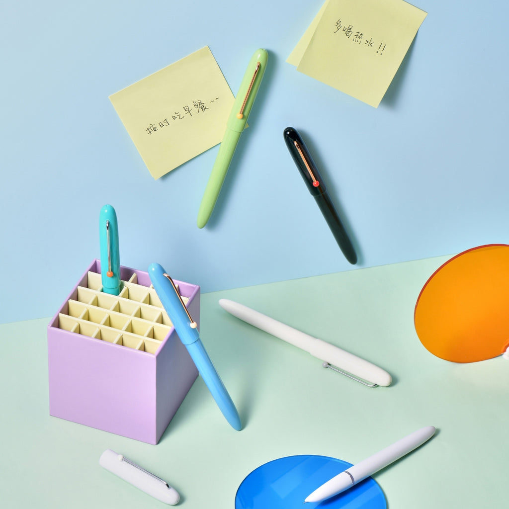 Colourful Kaco Retro pens arranged in a playful desk scene with sticky notes and accessories.