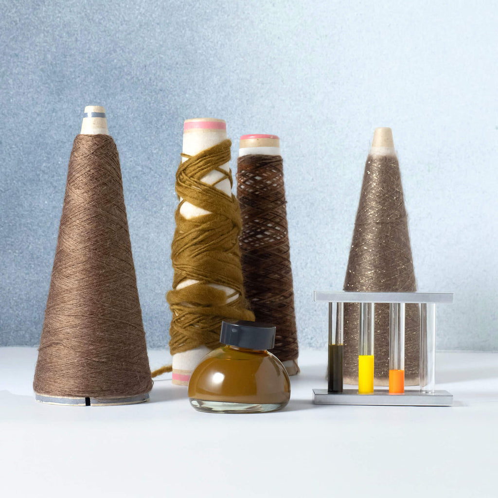 The Journal Shop - Kakimori Colour Specimen Ink bottles displayed with yarn cones and test tubes, inspired by textile ink 202.