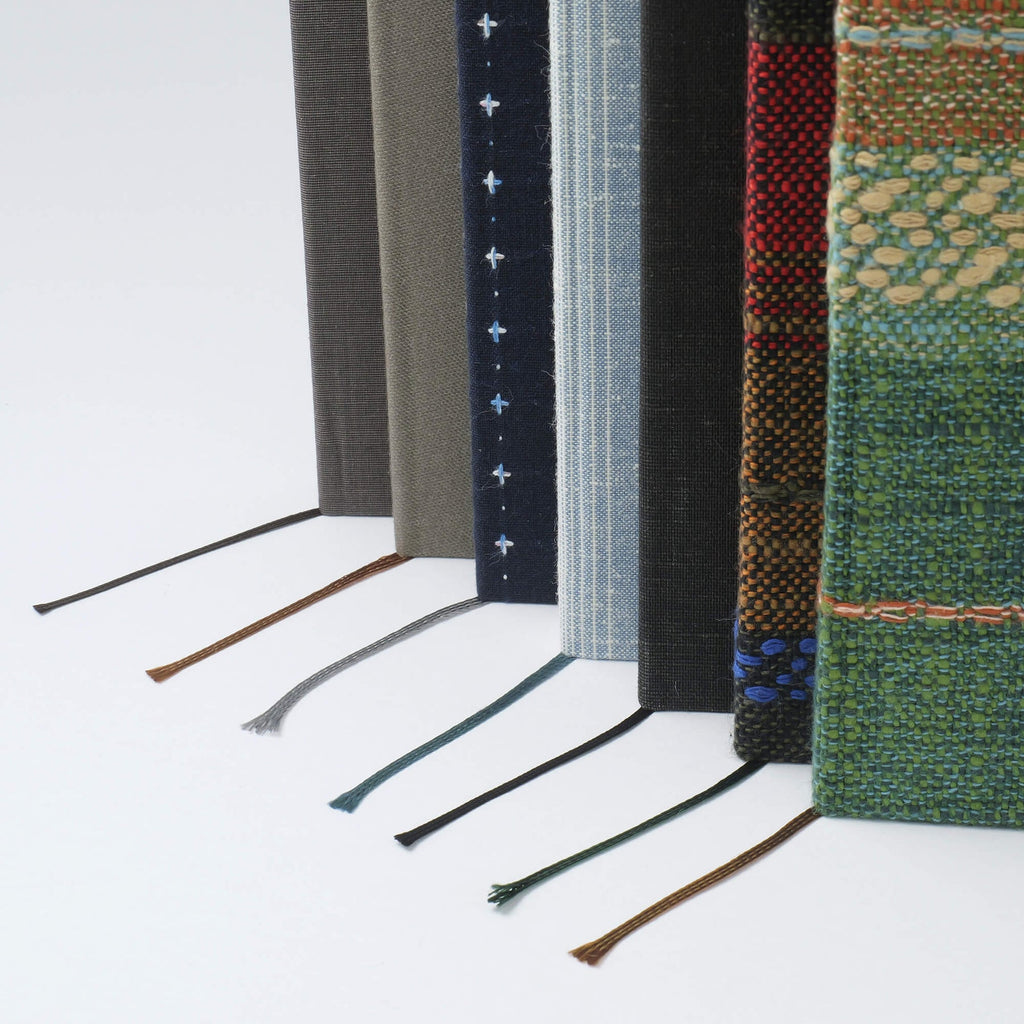 The Journal Shop - Kakimori Enshu Orimono A5 Notebook - Row of Kakimori Enshu Orimono A5 Notebooks standing upright.