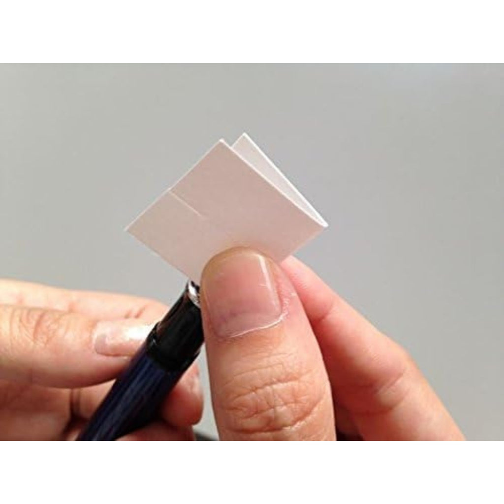 Close-up of folded SUITO cleaning paper being used to clean a pen.