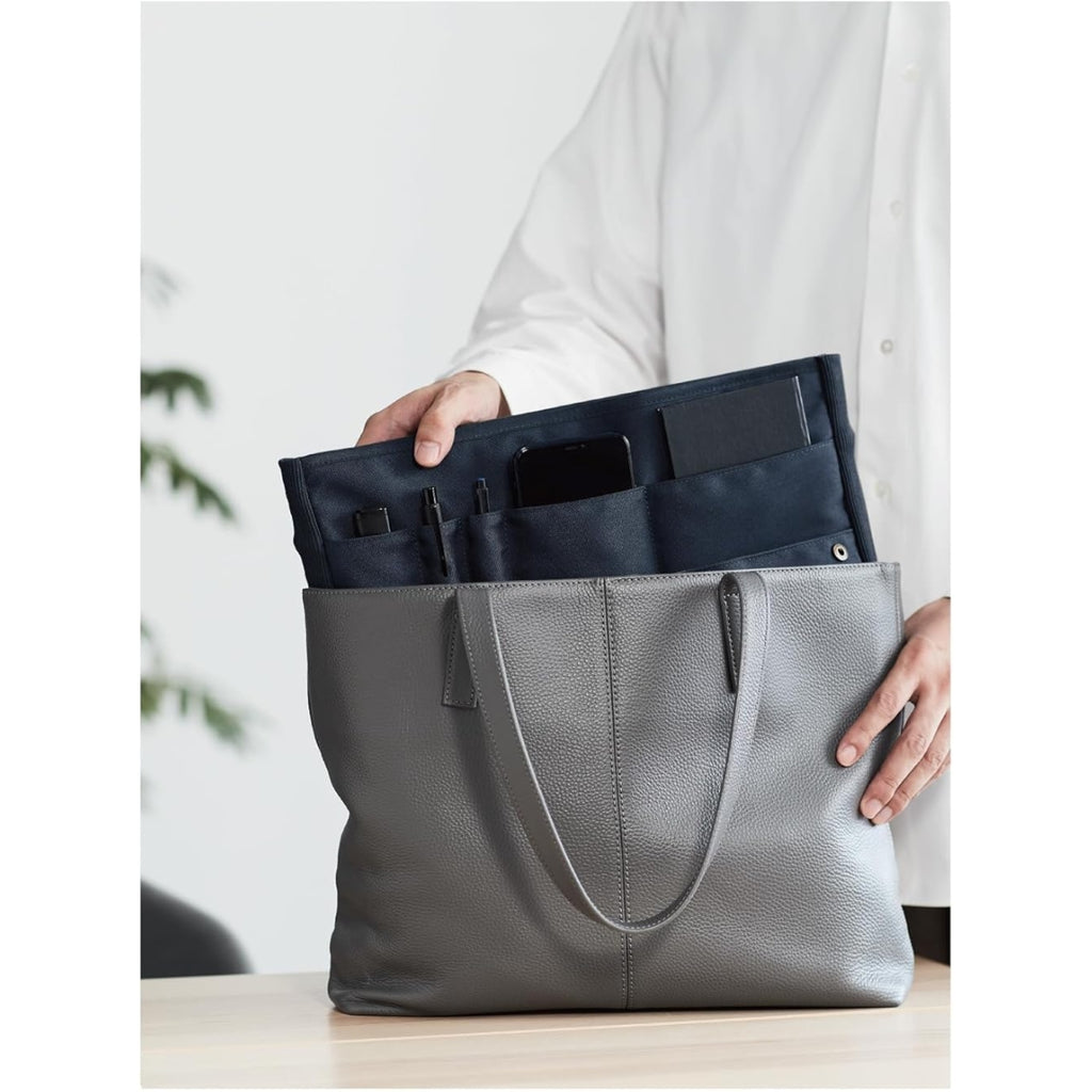Person placing a navy Kokuyo Bizrack Bag-in-Bag into a light grey shoulder bag.