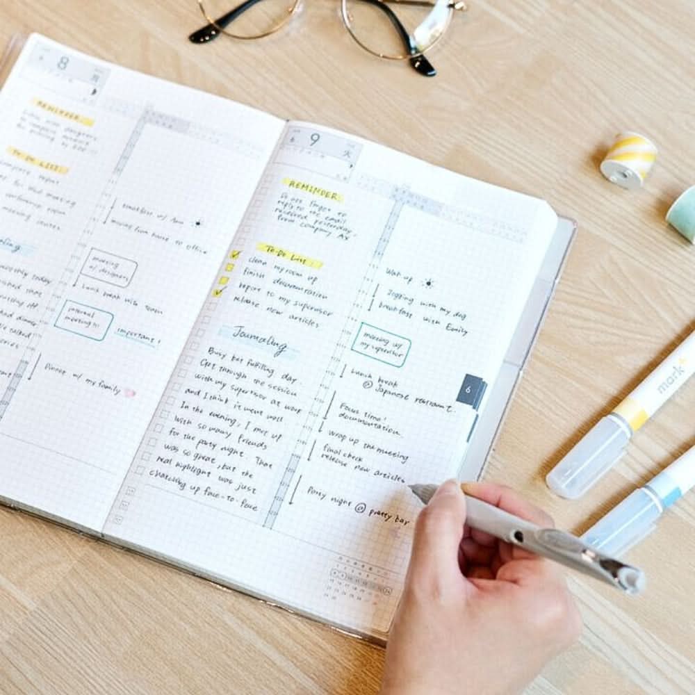 Person writing in Kokuyo Jibun Techo DAYs 2026 A5 Slim Daily Planner SOUSOU Limited Edition at a desk.