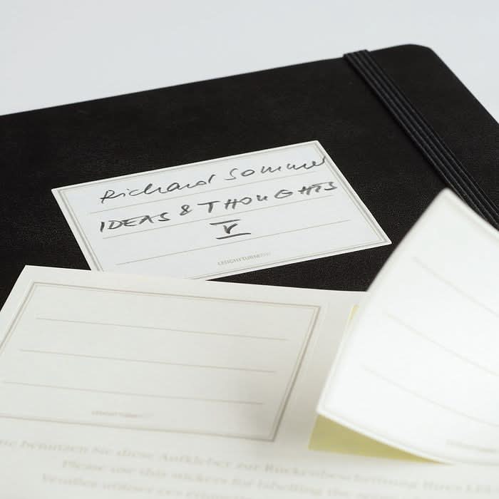 Close-up of a Leuchtturm1917 label sticker on a black notebook with handwritten text.