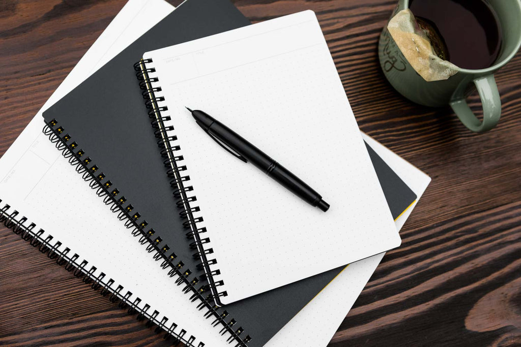 Maruman Mnemosyne A4 Planner Notebook on a desk beside a coffee cup and stationery.