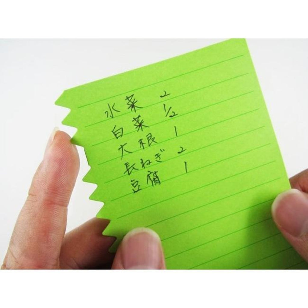 Close-up of a green Orissi notepad with handwritten Japanese text and distinctive zigzag edge.