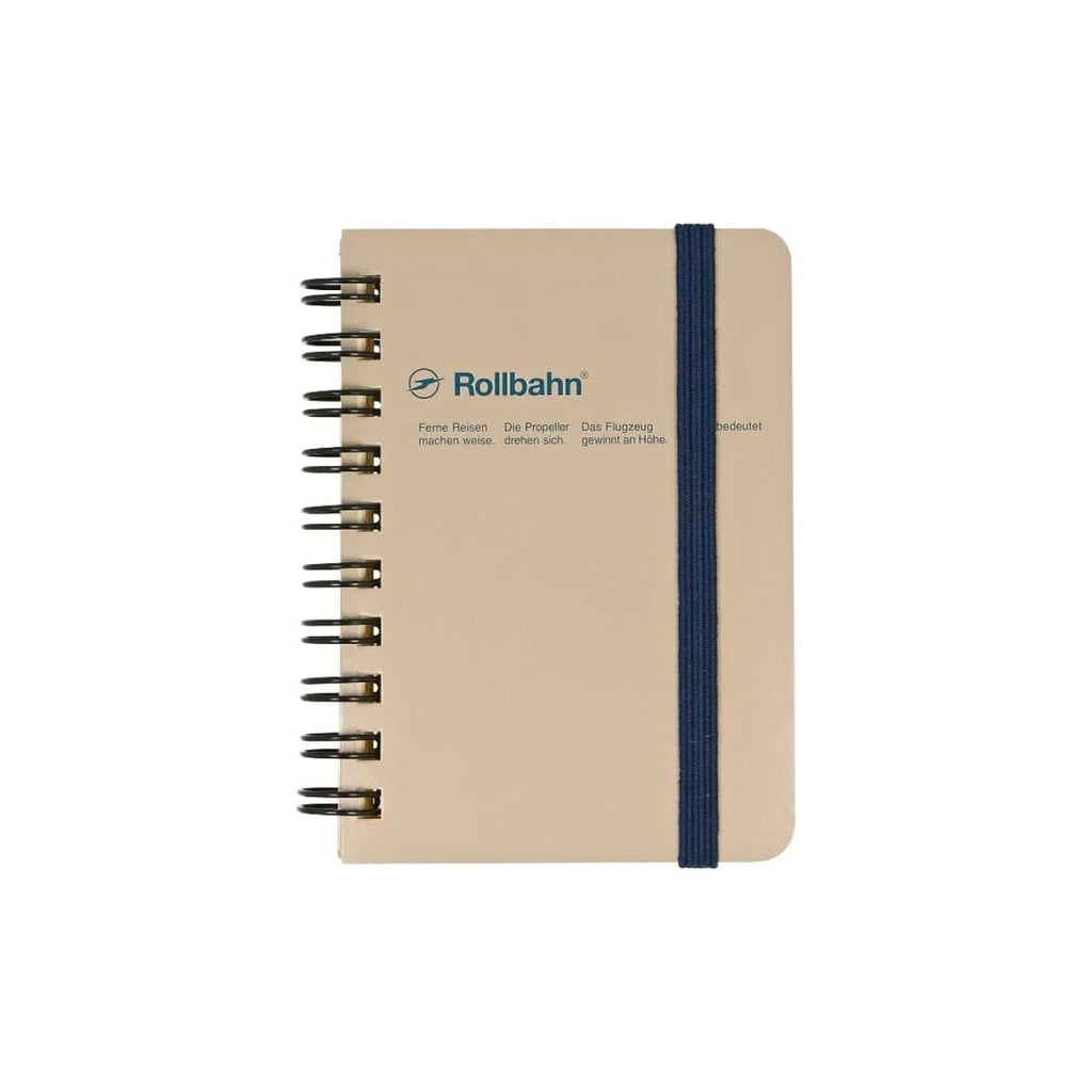 Beige pocket-sized Rollbahn notebook with navy elastic closure and black spiral binding.