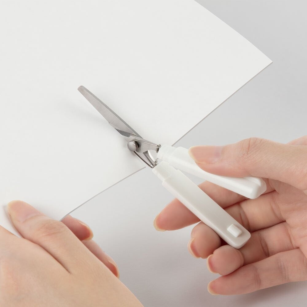 Sun-Star Stickyle compact scissors in white, being used to cut paper.