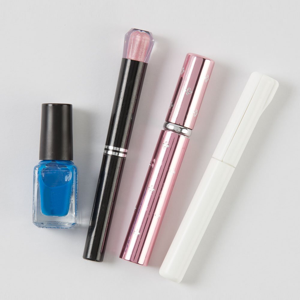 Sun-Star Stickyle compact scissors in white, shown alongside nail polish and cosmetic items for size comparison.