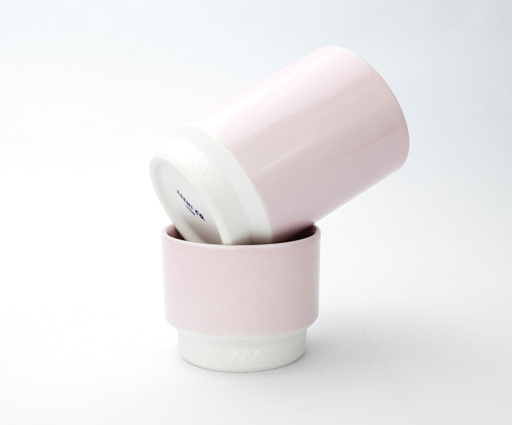 Two Asemi Hasami small cups in light pink stacked together, showing the soft glazed exterior and white base.